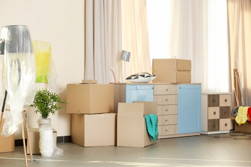 Removal team carrying furniture through a flat in Earls Court with stair access